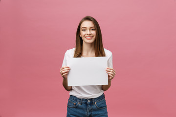Close up portrait of positive laughing woman smiling and holding white big mockup poster isolated on pink background