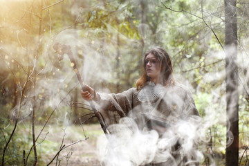 Obraz na płótnie Canvas A man in a cassock spends a ritual in a dark forest