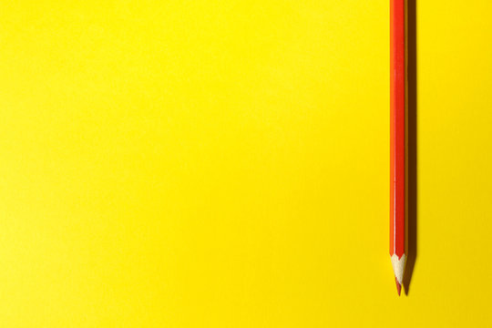 Red pencil on a bright yellow background. Place for text. top view