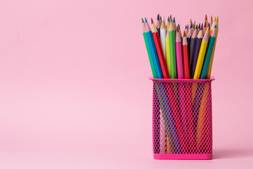 many colored pencils in a pink glass on a bright trendy pink background. space for text