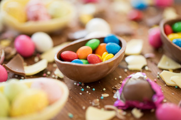Fototapeta na wymiar easter, junk-food, confectionery and unhealthy eating concept - close up of chocolate eggs and candy drops on table
