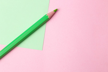 composition with green pencil on a pink and green background. top view. space for text