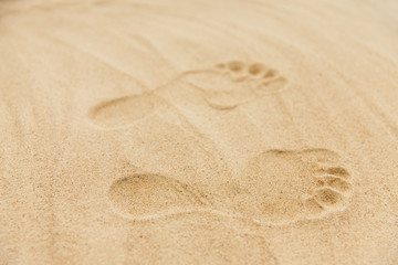 Fototapeta na wymiar summer vacation concept - footprints in sand on beach