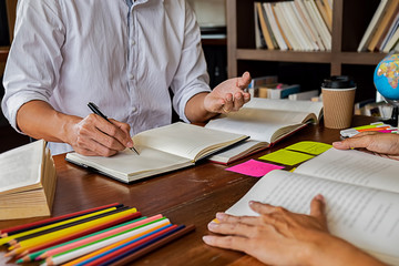 Education concept. Students studying and brainstorming campus concept. Close up of students discussing their subject on books textbooks and writing to notebook. Selective focus.