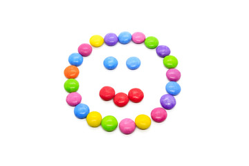 Smiley from multicolored chocolate glazed candies on white