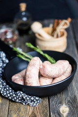 Raw grilled pork sausage with spices on old wooden background