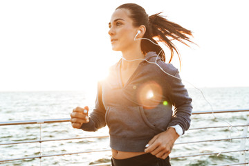 Young sports fitness woman running at the beach outdoors.