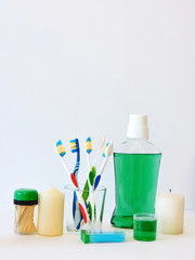 Fototapeta na wymiar Bottle and glass of mouthwash on bath shelf with toothbrush. Dental oral hygiene concept. Set of oral care products.Flat lay composition with manual toothbrushes and oral hygiene products. 