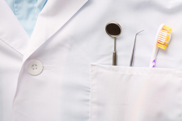 Closeup of dental tool, toothbrush and a mirror in white medical uniform pocket. Oral dental health...