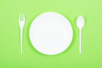 Empty Round white plate with spoon, fork on green background. Cuisine, Cooking, kitchen, Menu Restaurant mockup