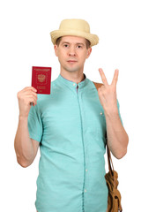 The man with the international passport, in a summer shirt, a hat and a traveling bag. Shows two fingers, gesture - a victory