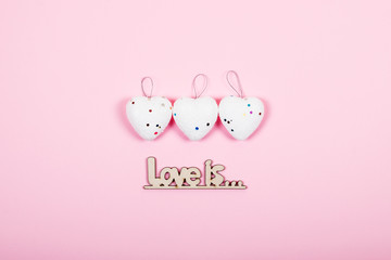 Valentines day pastel minimal creative background. Three white hearts with text Love is on pink background. Valentines day, Love, romance, wedding concept