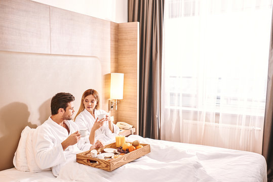 Fresh Fruits Breakfast. Couple Are Eating In Hotel Room Bed