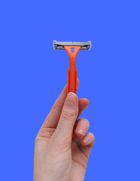 Razor in a man hand on a white background. Removal of unwanted hair. top view. Concept of using razor. Orange men's disposable razors. Shaving razor instrument.beauty, skin care concept 