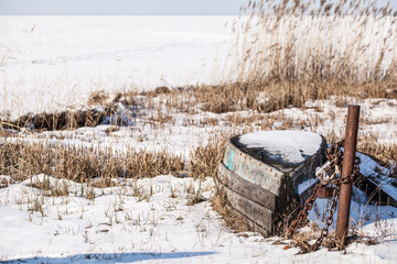 Old abandoned wooden broken boat under white snow on beach, panoramic view of winter landscape in the national park