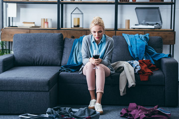 depressed woman sitting with glass of red wine while packing in living room after breaking up with...