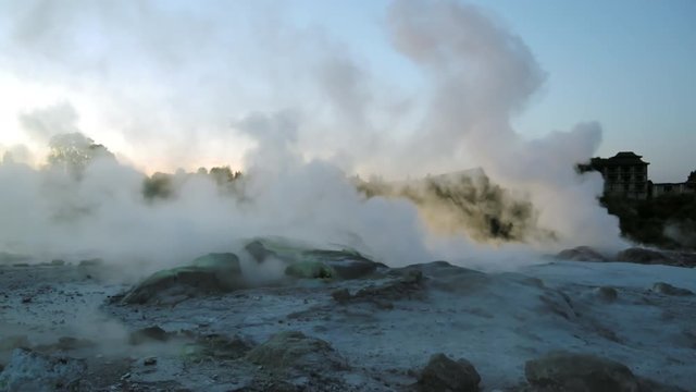 Medium shot of clouds of steam rising over rough volcanic landscape