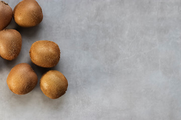 Ripe whole kiwi on a gray background.