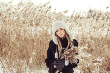 Young pretty attractive blonde girl with blondie hair in winter season have a good time outdoors in warm hat