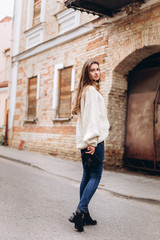 Portrait of young tender redhead young girl with healthy freckled skin wearing knitted scarf looking at camera with serious,pensive expression. Caucasian teen model with ginger hair posing outdoors