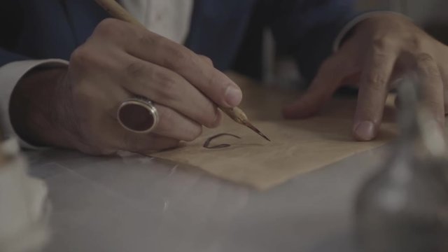 Male hand start writing calligraphic Arabic text