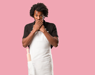 Handsome african american baker covering mouth, symbol of silence and repression, trying not to say anything