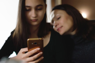 Two nice girls are sitting in a cafe and using mobile phones.