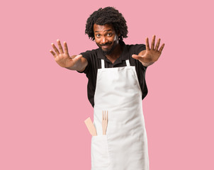 Handsome african american baker serious and determined, putting hand in front, stop gesture, deny concept