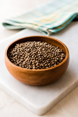 Organic Dried Coriander Seeds in Wooden Bowl.