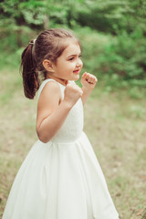 Outdoor portrait of cute brunette emotional girl dancing and having fun in elegant fashionable dress. Childhood, nature, fashion concept