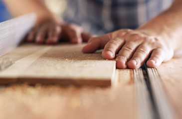 Craftsman sawing planks of wood in his carpentry workshop