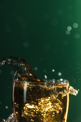 glass of beer with splashes isolated on green with copy space, isolated on green