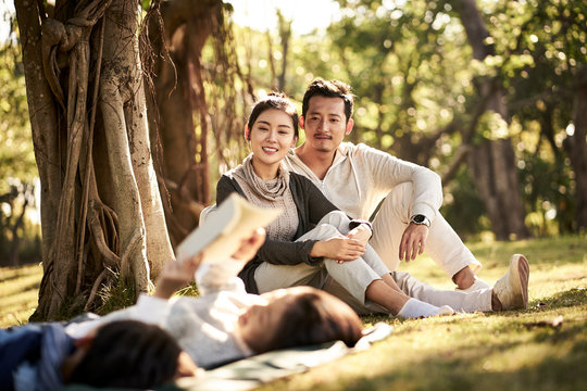 asian family with two children relaxing in park