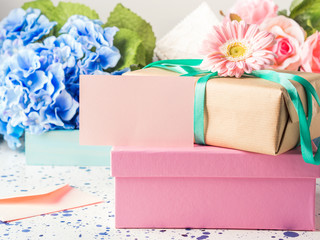 Blank pink card and stacked gift boxes. Flowers
