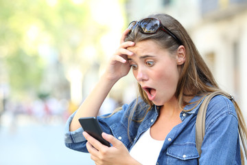 Shocked teen checking phone content in the street