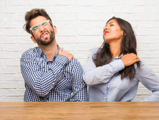 Young indian woman and caucasian man couple with back pain due to work stress, tired and astute