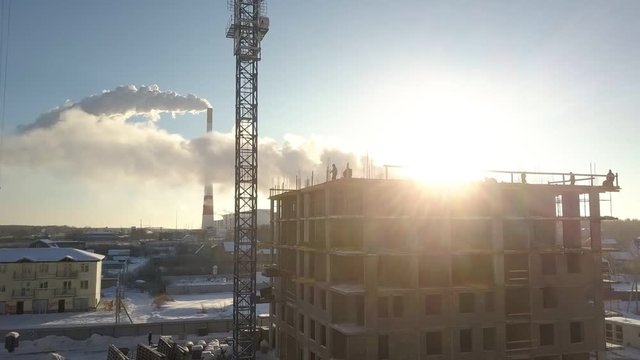 upper view morning sun shines from behind uncompleted building near electric power station on frosty winter day