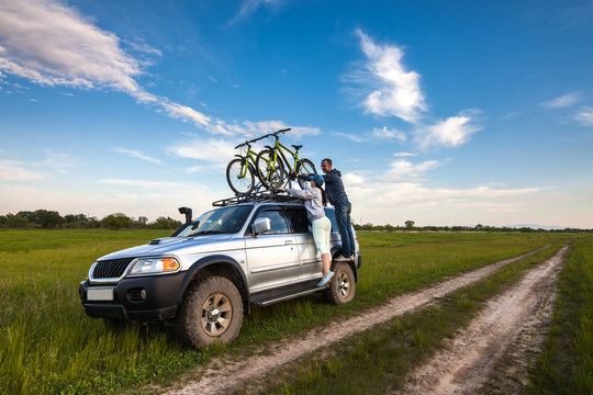 Couple taking off their bicycles from roof rack