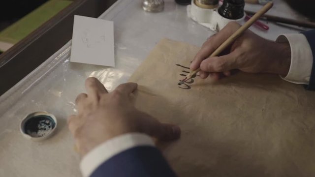 Point-of-view shot male hand writes a pen calligraphic arabic letters