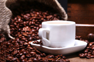 Fresh roasted coffee beans in burlap sack, espresso in cup and grinder on stone background.