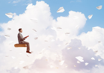 Businessman or student reading book and paper planes flying around