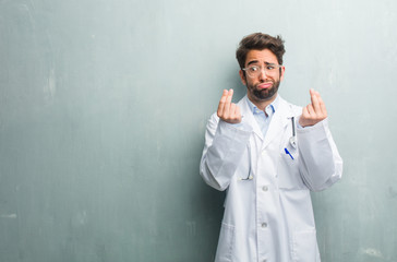 Young friendly doctor man against a grunge wall with a copy space sad and depressed, making a...