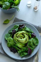 Salad mix with avocado, spinach and beet leaves on gray wooden background. Vegetarian food concept. Selective focus.
