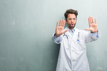 Young friendly doctor man against a grunge wall with a copy space serious and determined, putting...