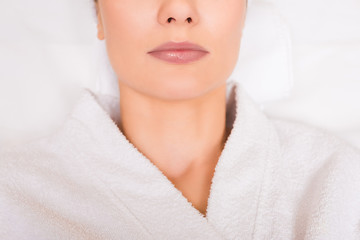 Obraz na płótnie Canvas cropped view of woman lying in white bathrobe at beauty salon