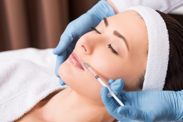 Obraz na płótnie Canvas cosmetologist doing injection on woman lip at beauty salon