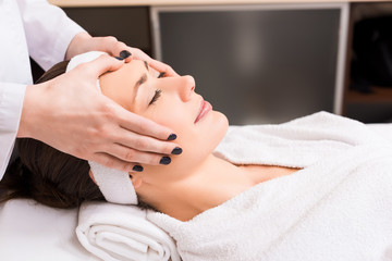 Fototapeta na wymiar cosmetologist giving manual face massage to woman at beauty salon
