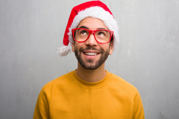 Young man celebrating christmas day holding gifts dreaming of achieving goals and purposes
