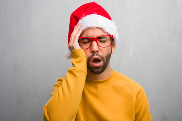 Young man celebrating christmas day holding gifts tired and very sleepy