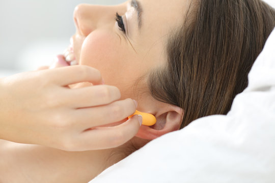 Close up of a woman hand putting ear plugs to sleep
